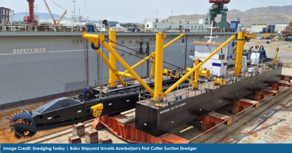 A high-powered Cutter Suction Dredger (CSD650) named Engineer Soltan Kazimov docked at Baku Shipyard, surrounded by industrial structures and shipbuilding equipment. The dredger features a large cutter head at the bow, modular side pontoons, and a prominent operator cabin. The background shows cranes and construction activity, highlighting the shipyard’s active maritime engineering operations.